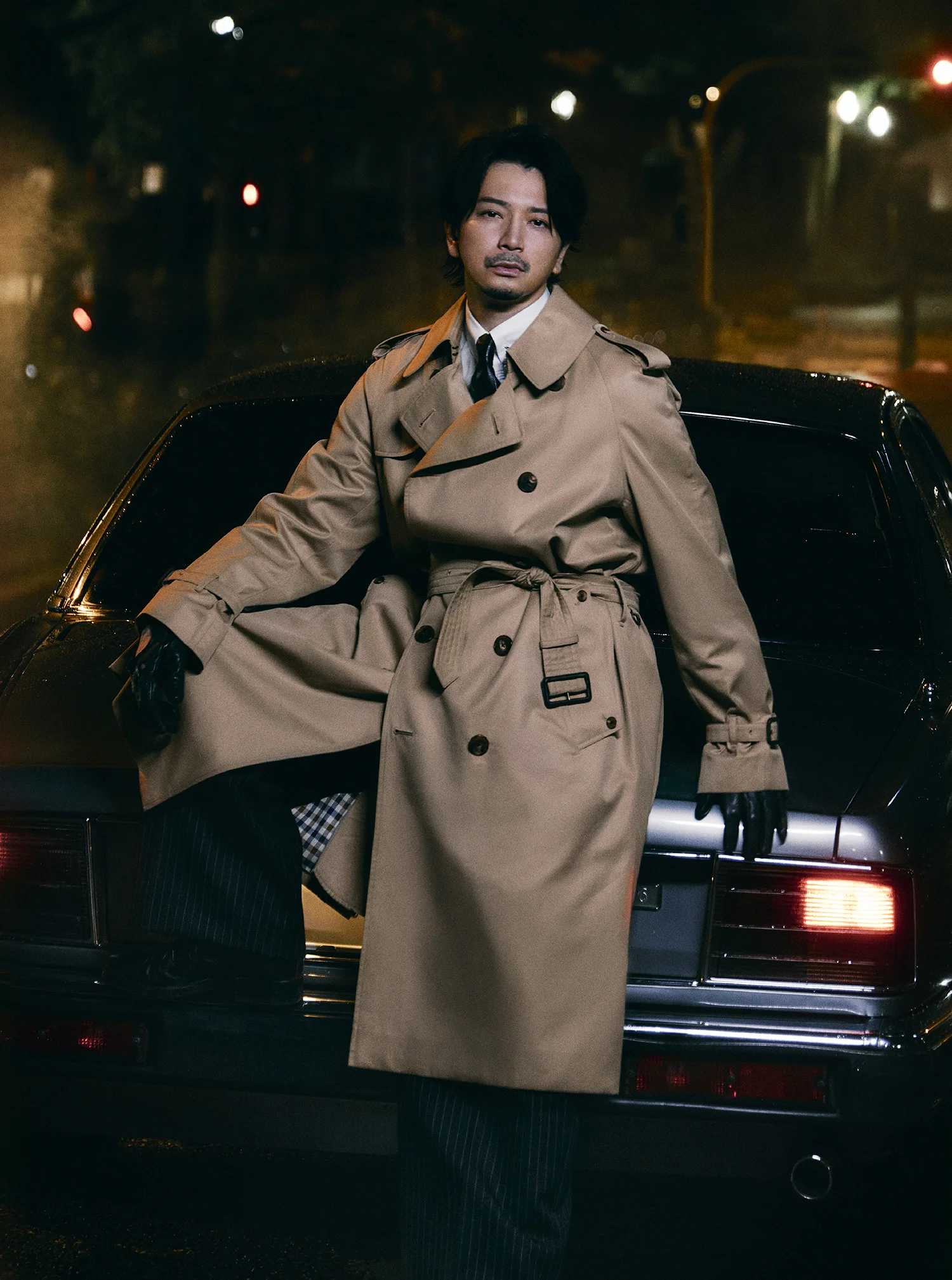 Jun Matsumoto standing in front of a car at night